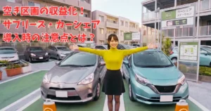 カーシェアステーションに立つマンション管理フロントのあおい。黄色いトップスと黒タイツの衣装で、両手を広げて笑顔で紹介している様子。